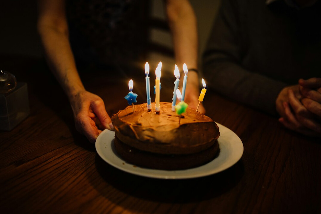 Elderly Swiss friends celebrating a birthday with a cake at a community table