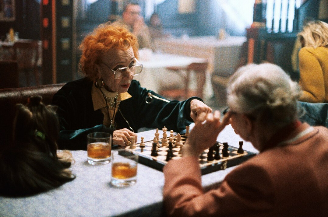 Two elderly men playing chess at a community club table